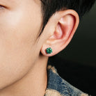Green cubic zirconia stud earrings worn close up